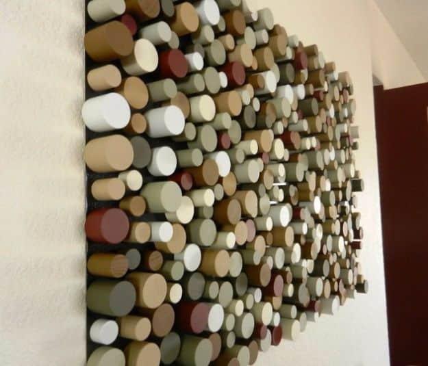 Wall panel of hundreds of painted dowel slices in cream, olive, tan and white standing out at varying depths