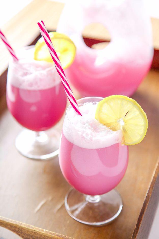 Glasses of frothy pink raspberry sherbet punch with striped paper straws and lemon slices on the rims