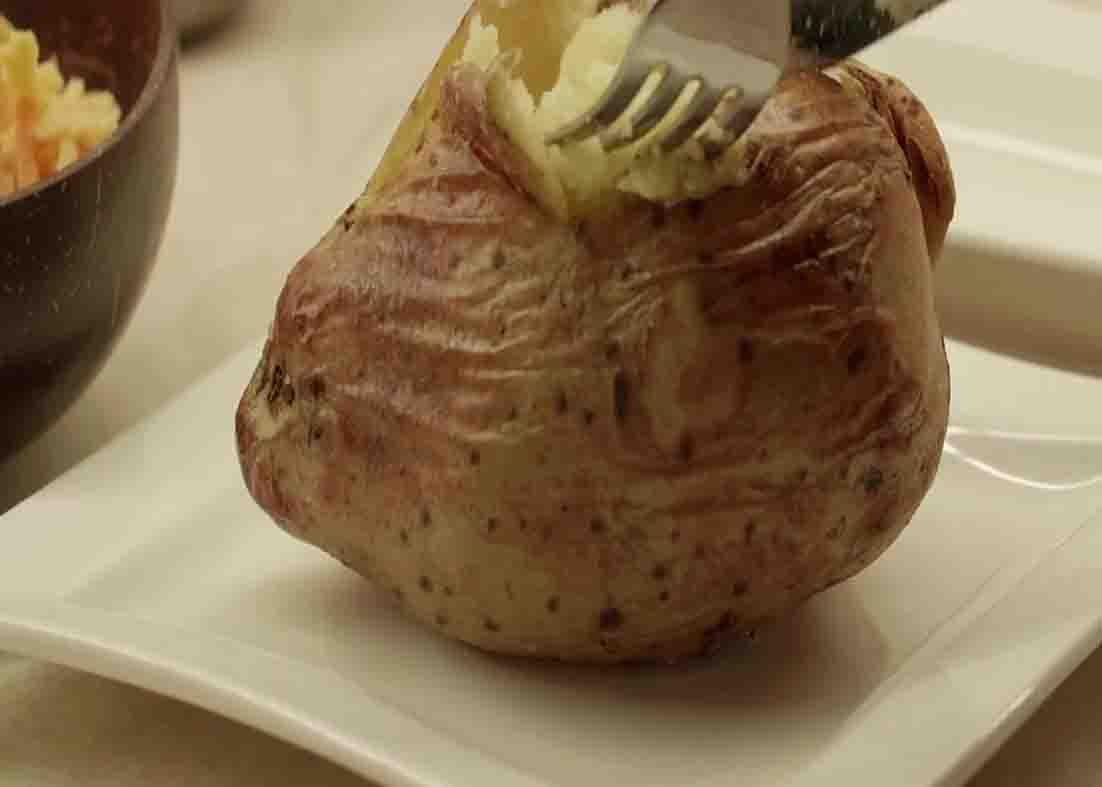 Filling the potatoes with butter and cheese and seasoning with salt and pepper