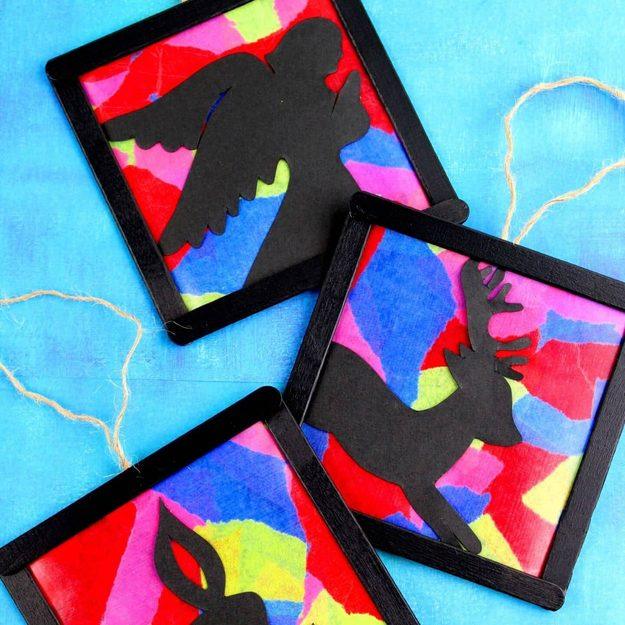 DIY stained glass ornaments, three black craft stick squares filled with torn bright tissue paper and black bird silhouettes