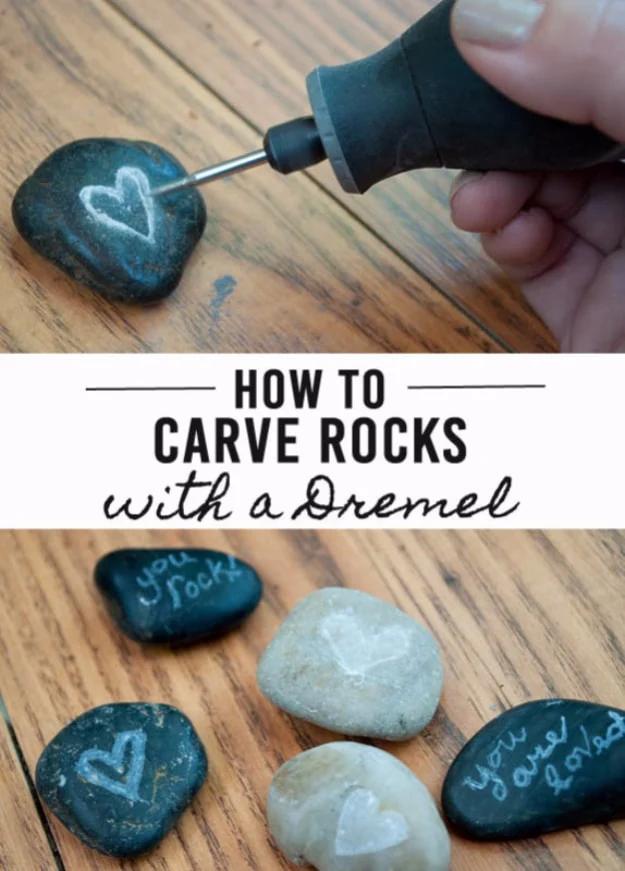 A Dremel carving a heart into a dark rock, above five finished rocks carved with hearts and short messages