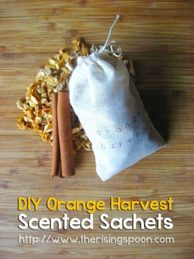 Small stamped muslin drawstring sachet on wood with cinnamon sticks and dried orange peel scattered around it