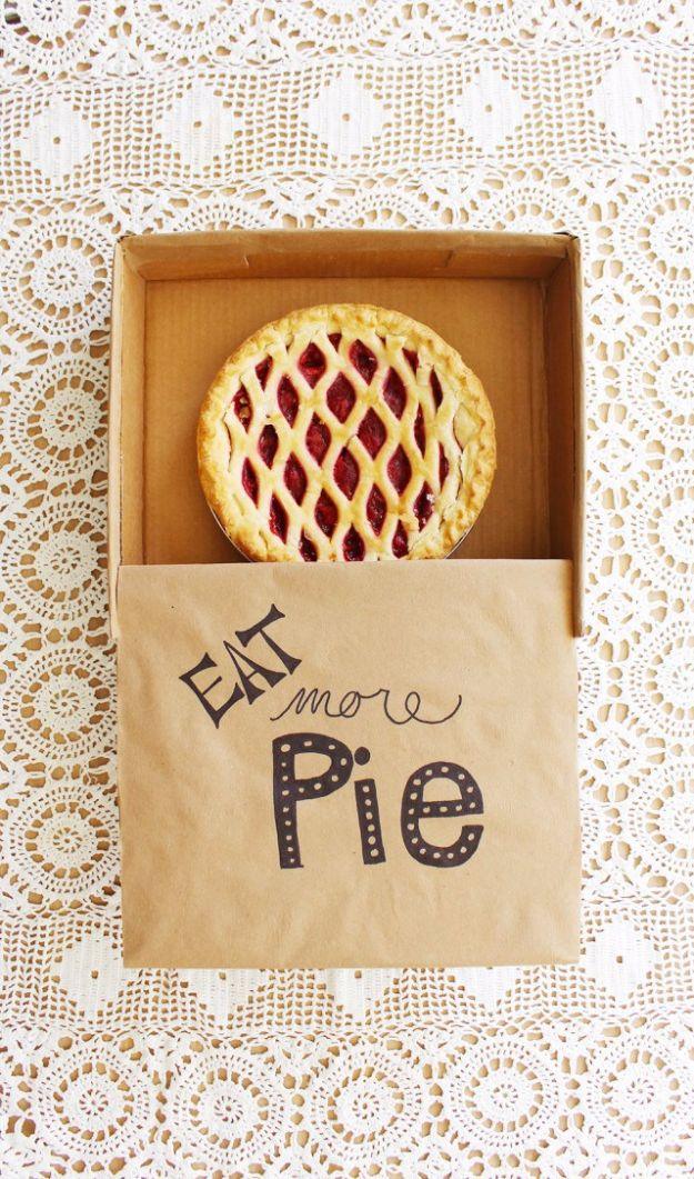 Cardboard craft kraft pie box holding a lattice topped pie with a hand lettered paper sleeve on a lace cloth