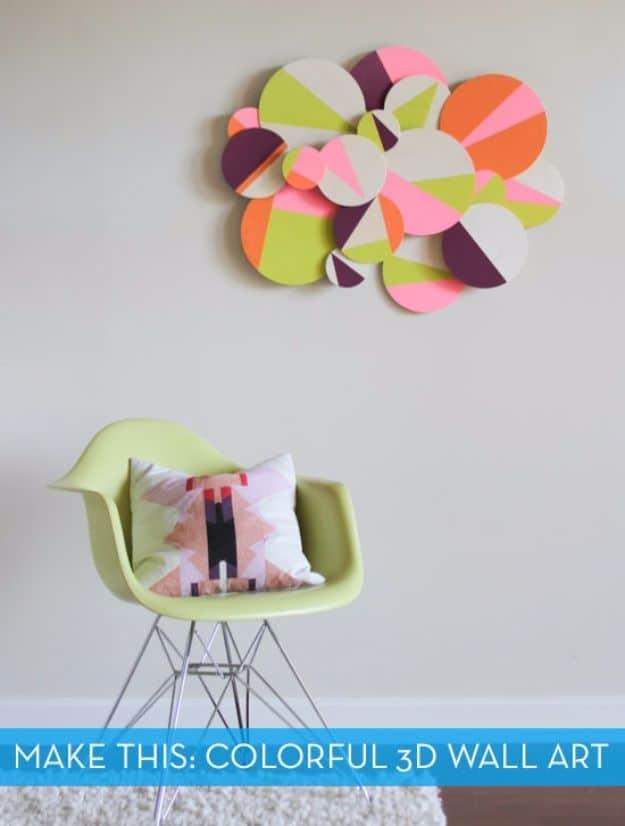 Cluster of painted wooden circles in pink, orange, green and cream mounted at varying depths on a pale gray wall