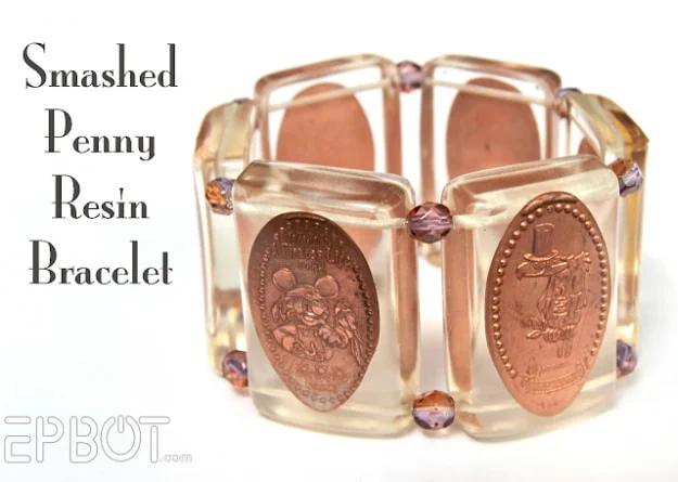 Stretch bracelet of souvenir smashed pennies cast in clear resin tiles with faceted beads, beside typeset lettering