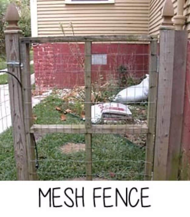 Mesh fence, a welded wire gate framed between wooden posts with finials, with a red barn standing behind the grassy yard