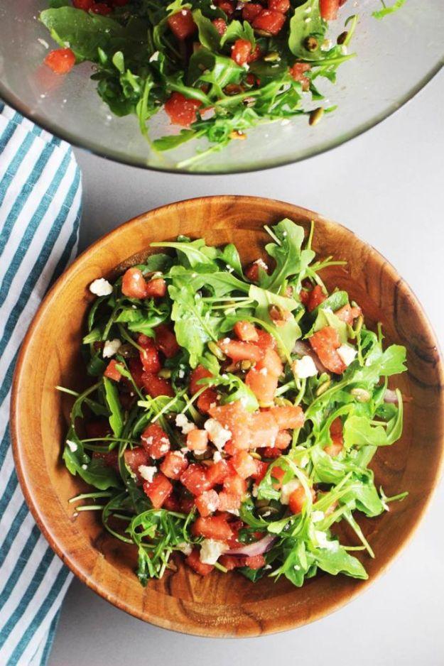Mexican watermelon salad with arugula, diced watermelon, queso fresco and toasted pepitas in a wooden bowl