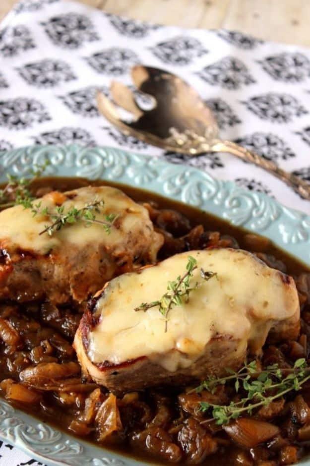 French onion pork chop buried under melted browned cheese and deeply caramelized onions with fresh thyme