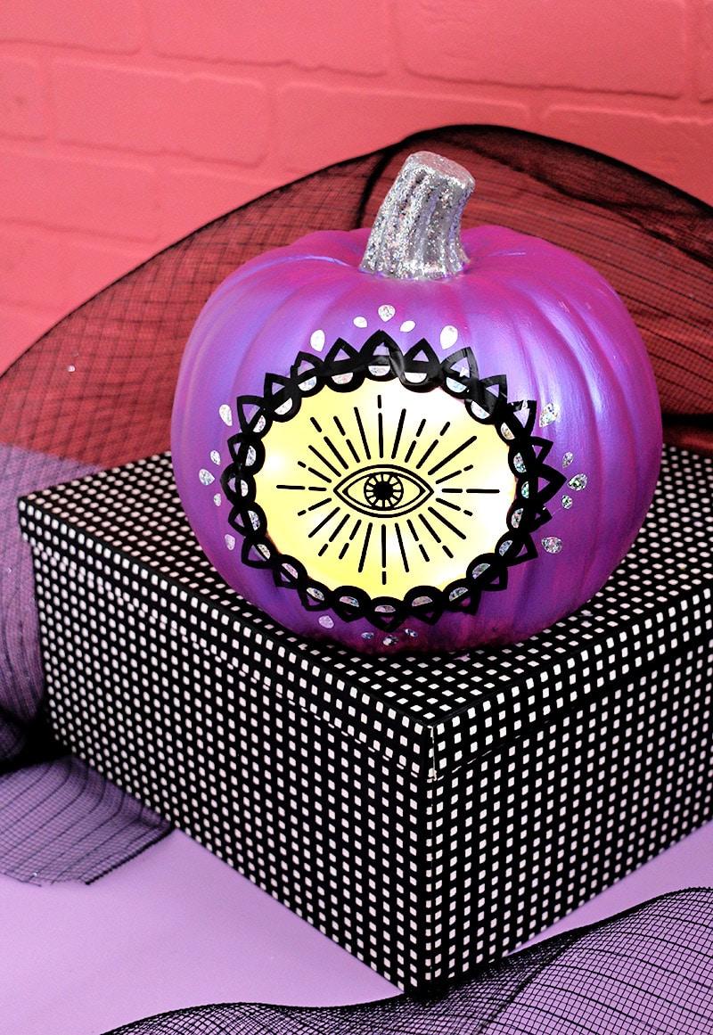 Painted craft pumpkin glows through a large layered mystic eye design lit from inside with battery lights
