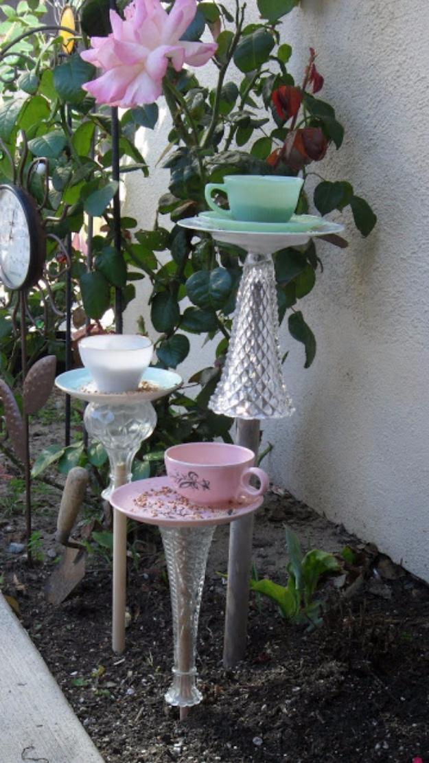 DIY teacup bird feeder, pastel teacups and saucers glued to glass vase bases and staked in a garden flower bed