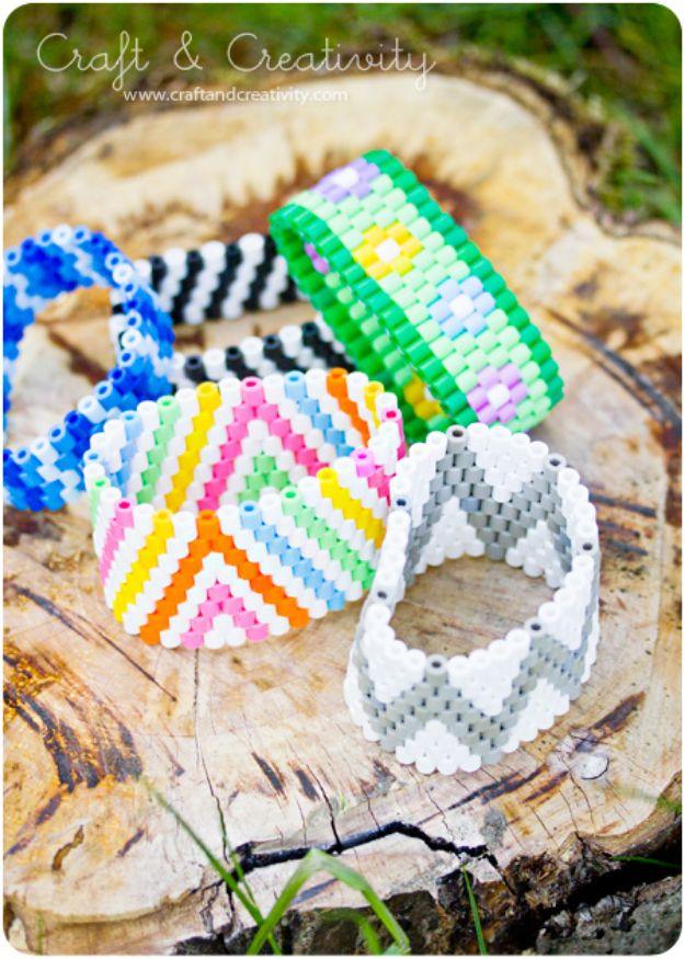Colorful cuffs, four wide beaded bracelets in chevron and diamond patterns resting on a cut log outdoors