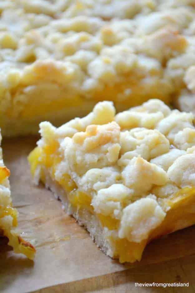 Jack Daniels peach pie bars cut into squares with a shortbread base, golden peaches and crumble topping