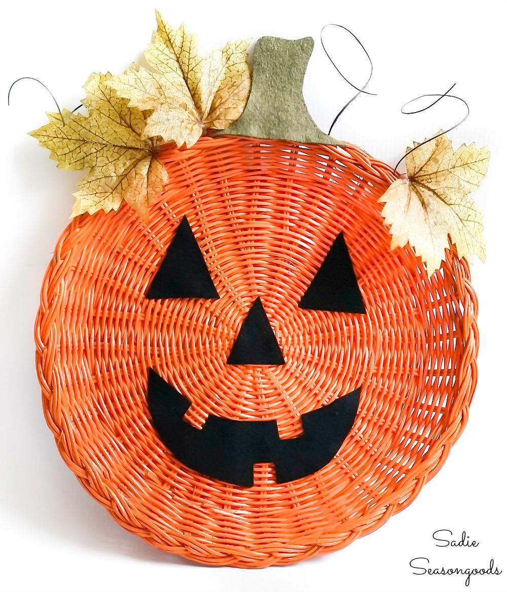 Orange wicker paper plate holder becomes a jack-o-lantern door hanger with felt face and green accents