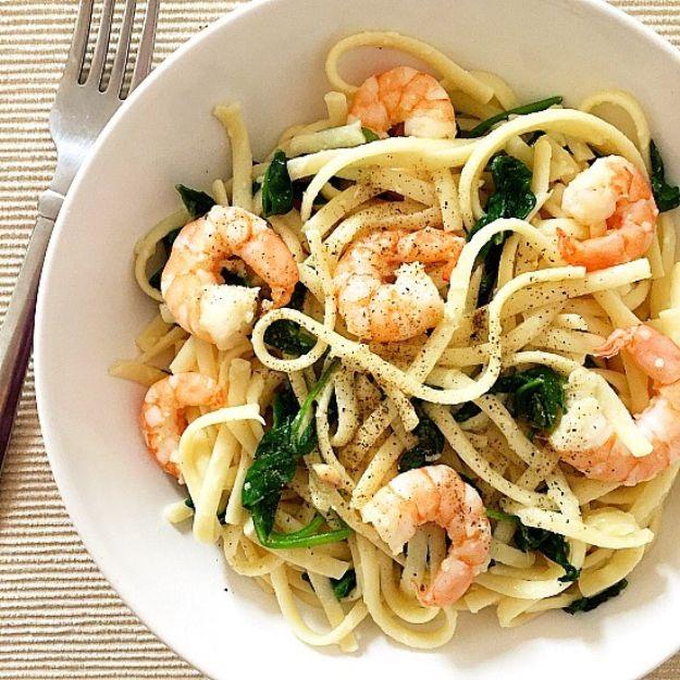 Pasta with shrimp and spinach in a white bowl, spaghetti with prawns, wilted spinach and black pepper