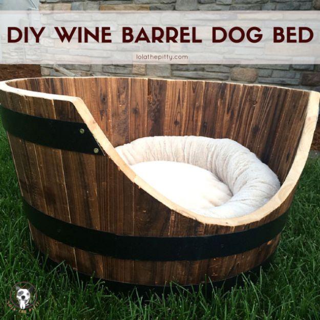 Wine barrel dog bed made from a half whiskey barrel cut into a curved opening with a round white cushion inside on grass