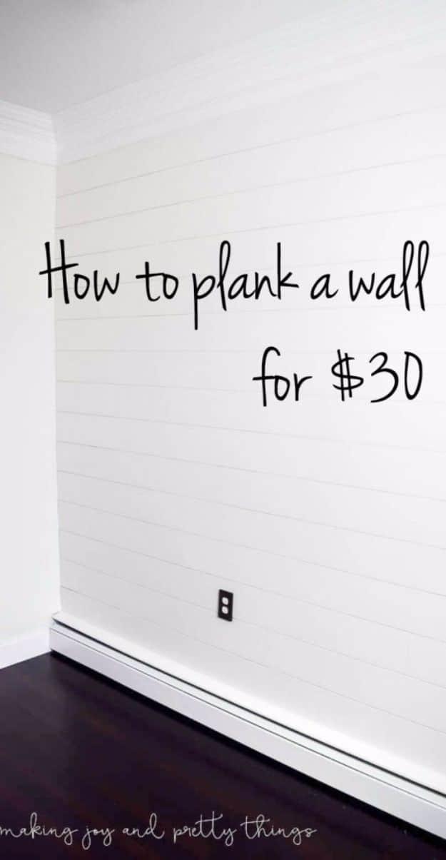 White planked shiplap wall above a white baseboard and a dark hardwood floor, lettered How To Plank A Wall For $30