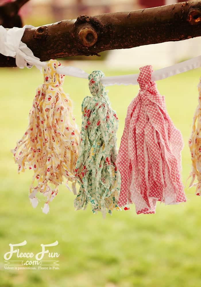 Ragged fabric tassels in yellow, green and pink floral prints, strung on white trim from a bare branch