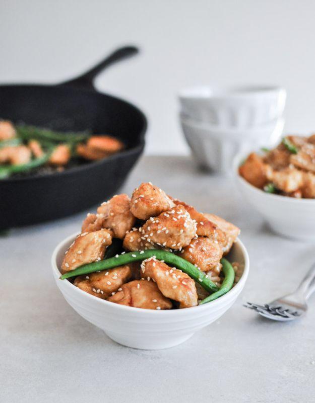 Healthy sesame chicken skillet, glazed chicken pieces with green beans and sesame seeds in a white bowl