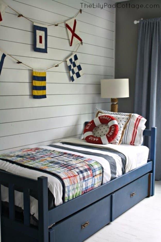 Navy blue chalk painted bed frame in a boy's nautical bedroom with white shiplap walls and a plaid quilt