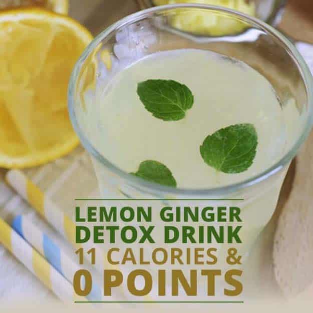 Lemon ginger detox drink in a clear glass with floating mint leaves, sliced lemons and a striped towel behind