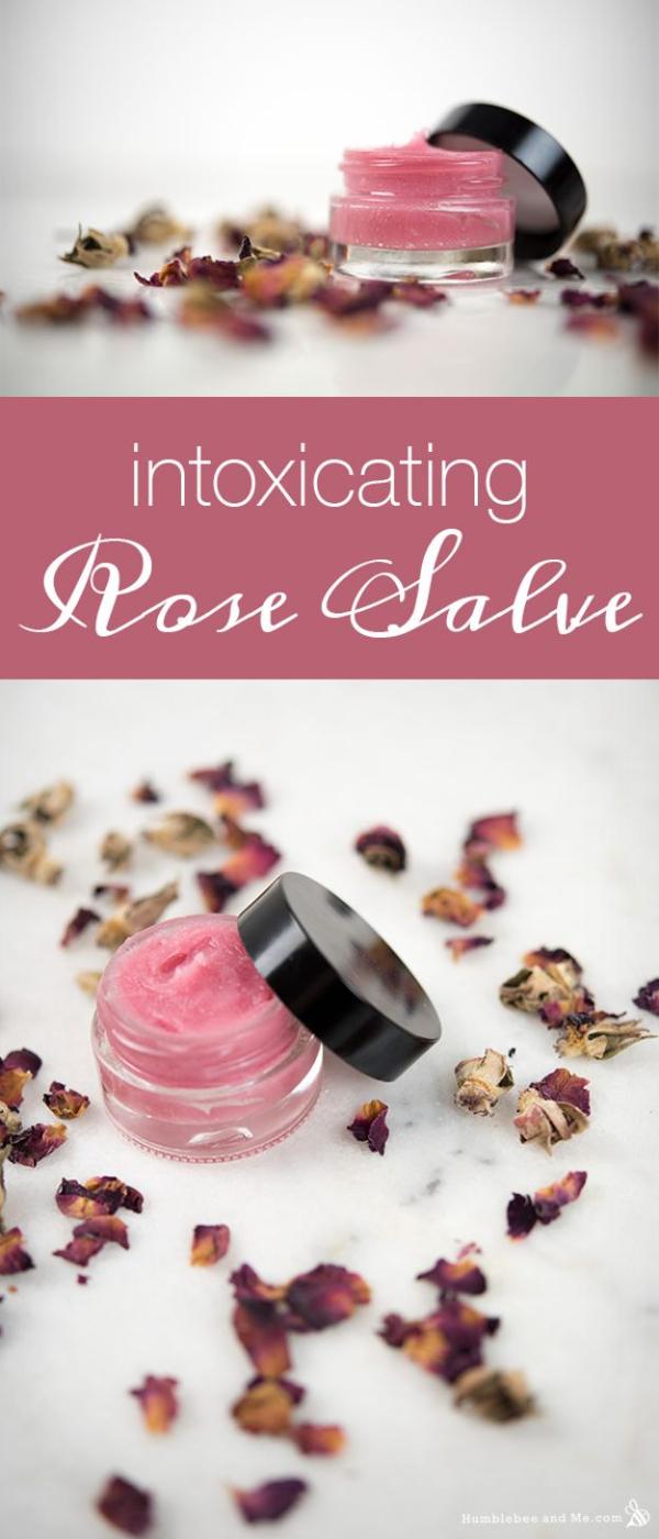 Rose salve in a small glass jar with a black lid on white marble with dried rose buds and loose petals