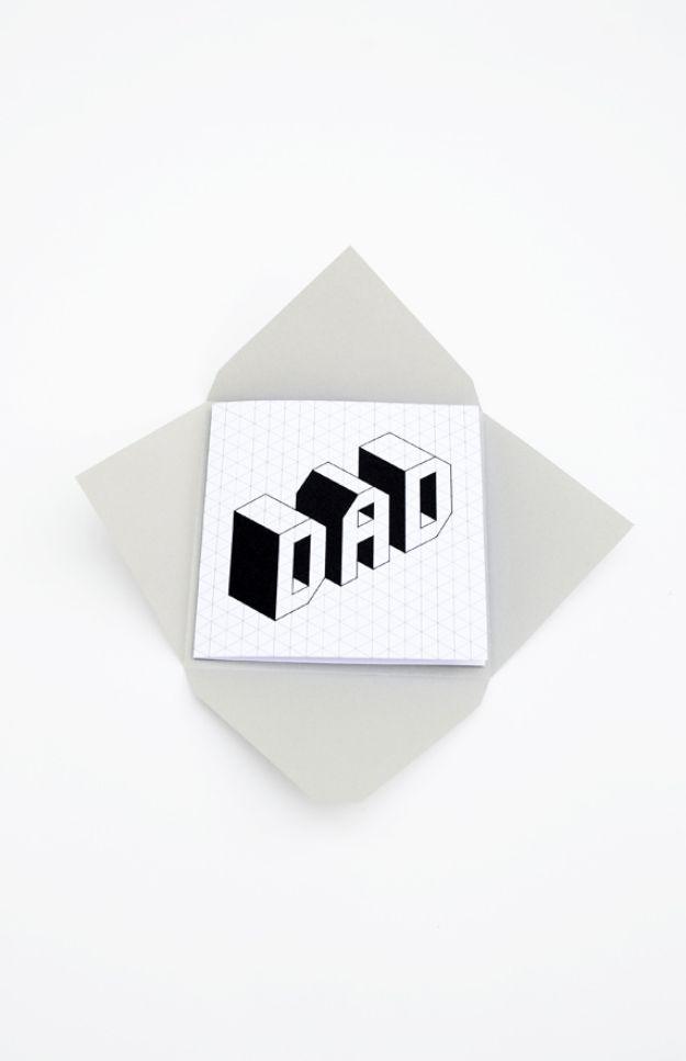 Minimalist Father's Day card with DAD in black isometric block letters on a fine grid over a gray envelope