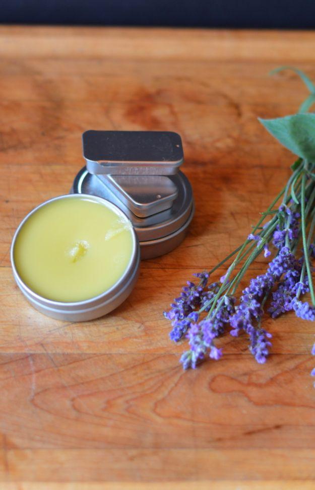 Small metal tin of pale green herbal headache salve, open on a wooden board with fresh lavender flowers