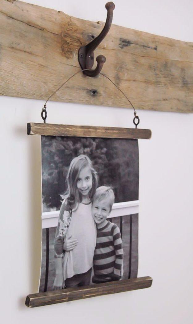 Black and white photo of two children mounted on canvas between stained wood battens, hanging by wire from a hook on a beam