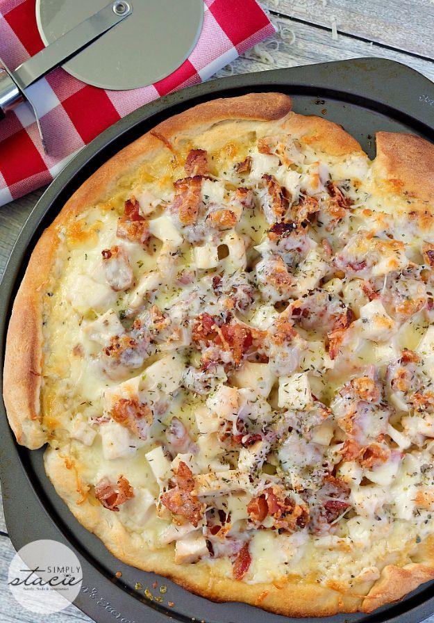 Round chicken Caesar pizza baked in a metal pan on a red checked cloth with a pizza cutter beside it