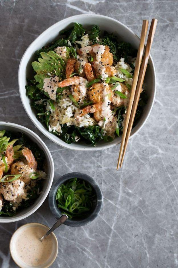 Spicy shrimp bowl with crispy rice, kale and avocado in a gray bowl with chopsticks and a sauce dish