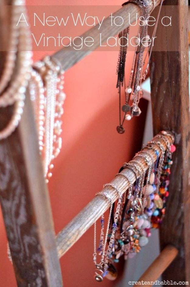 Vintage ladder jewelry holder, a chippy paint spattered wooden ladder hung with long beaded necklaces on a red wall