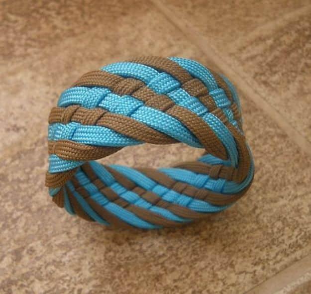Tan and turquoise paracord bracelet twisted into a spiral bangle rather than a flat knotted band, on tile