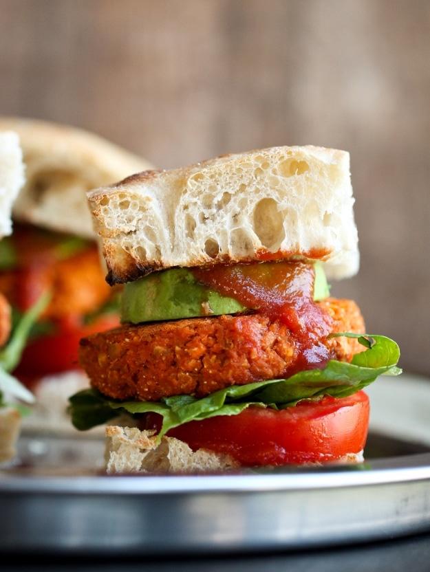Smoky barbecue sweet potato chickpea burgers on buns, baked with a crisp cornmeal crusted exterior beside the grill