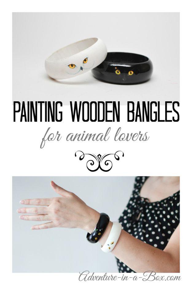 Two painted wooden bangles, white with owl eyes and black with cat eyes, above a photo of one worn on a wrist