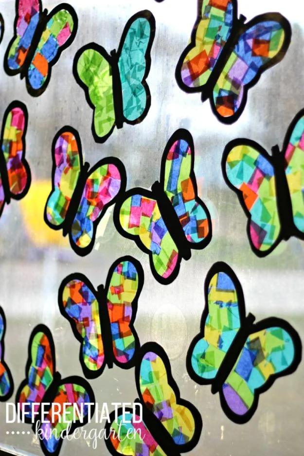Row of stained glass butterflies made from colored tissue paper in black paper frames, stuck to a bright classroom window