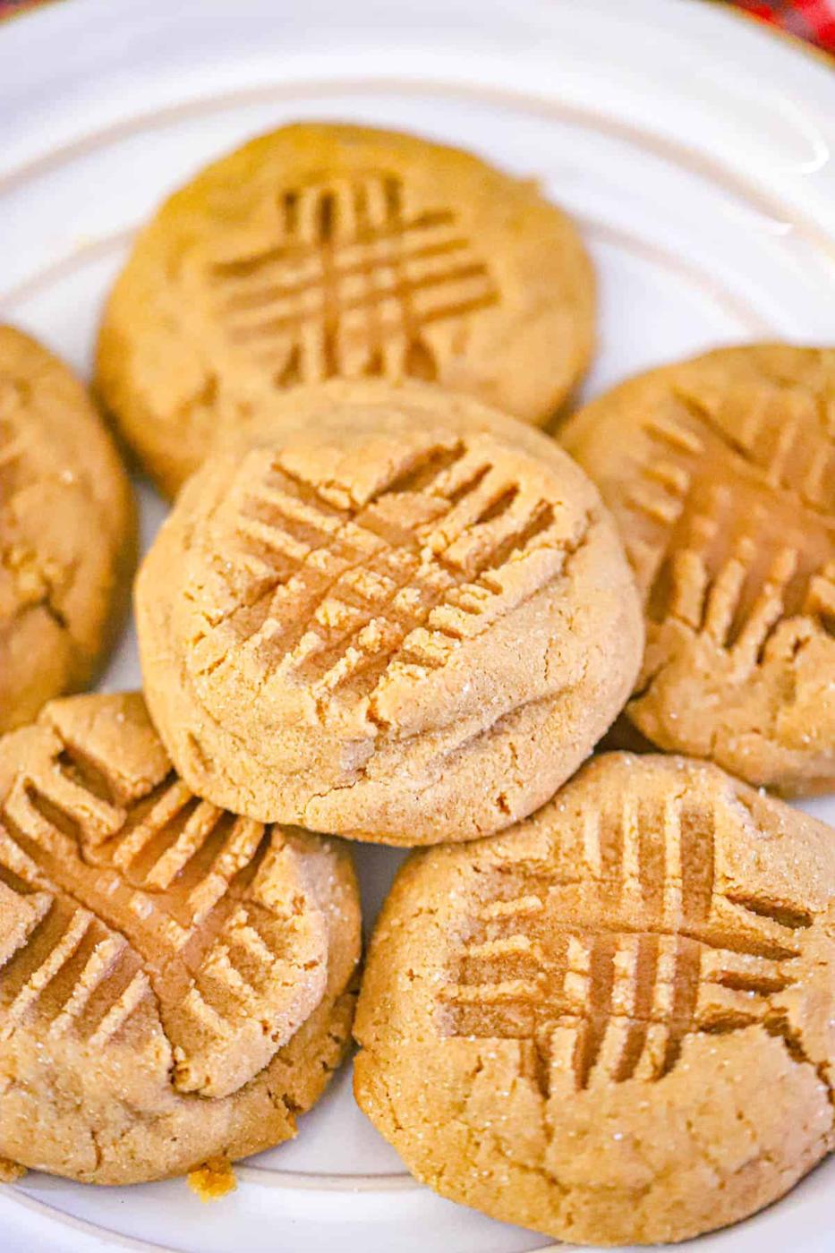 Thick sugar coated maple peanut butter cookies with crosshatch tops piled on a white plate with a gold rim