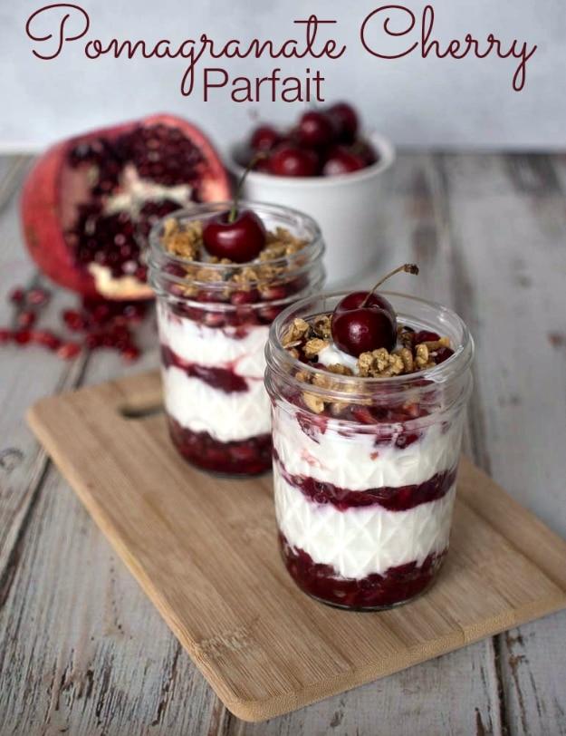 Pomegranate cherry parfait in a jar with warm fruit compote layered through plain Greek yogurt and granola