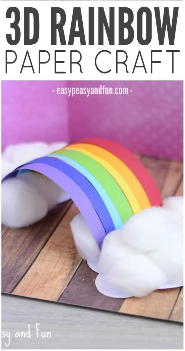 3D paper rainbow of seven colored strips arching between two paper clouds covered in cotton balls, on wood
