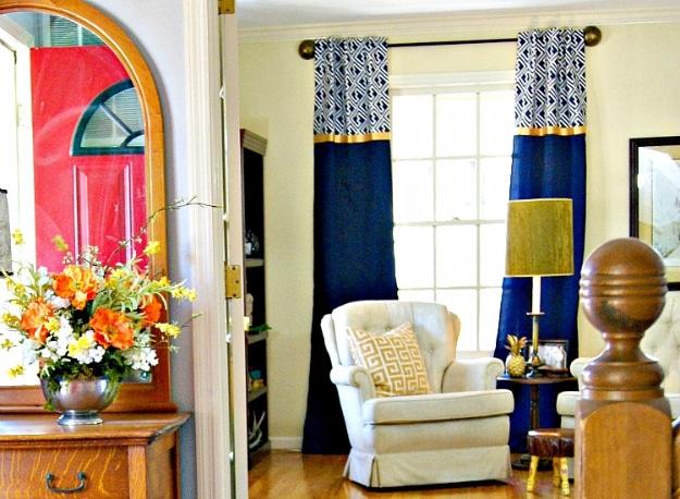 Navy curtain panels with a wide patterned band across the top, hung high in a bright entryway beside a red front door