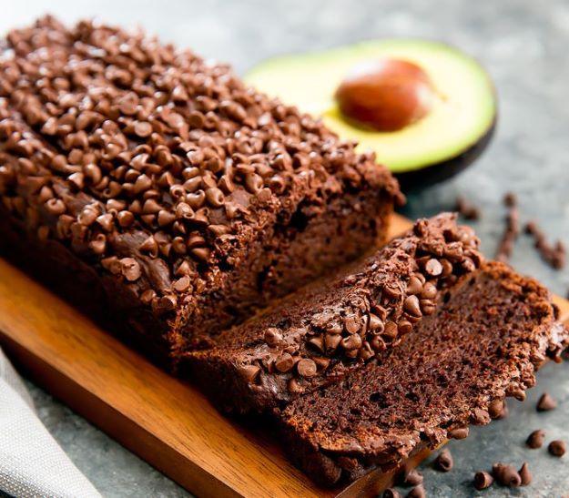 Chocolate avocado banana bread, a dark loaf covered in mini chocolate chips with two slices cut on a board