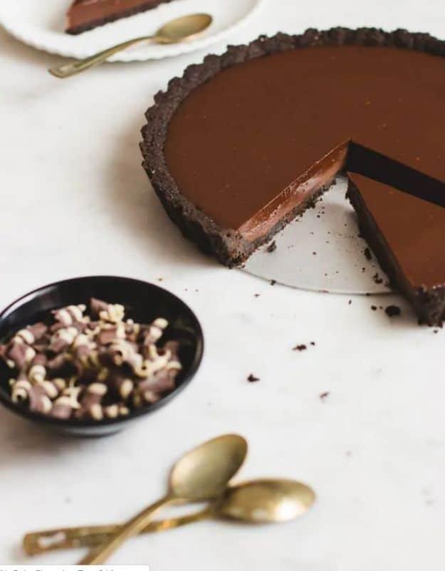 No bake chocolate tart with an Oreo crust and glossy chocolate ganache filling sliced on a plate, an easy no bake dessert
