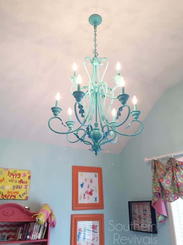 Hand painted chandelier makeover in soft aqua with white candle sleeves, hanging in a girls bedroom with framed art