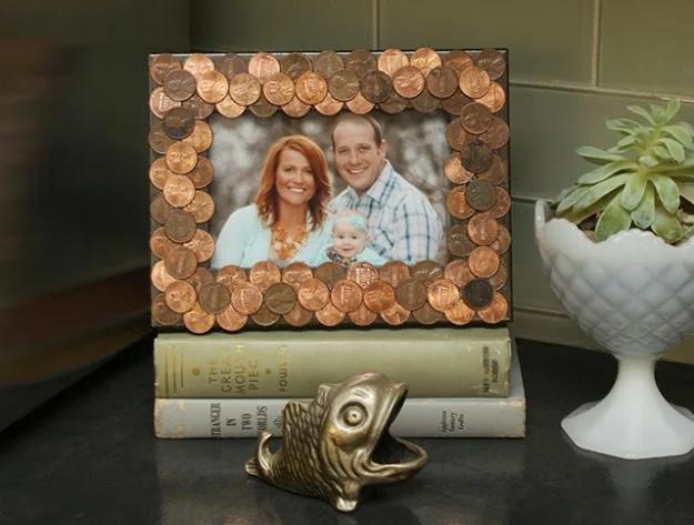 Penny photo frame covered in copper coins standing on old books beside a brass fish, holding a family photo