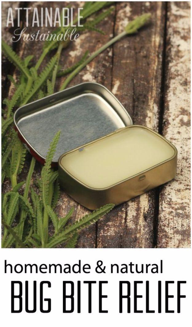 Small metal tin of pale yellow lavender bug bite balm open on weathered wood beside a green fern frond
