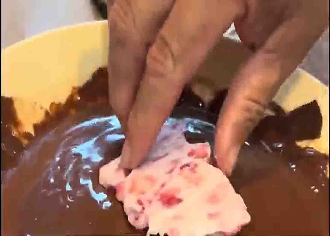 Coating the strawberry bites with chocolate frosting