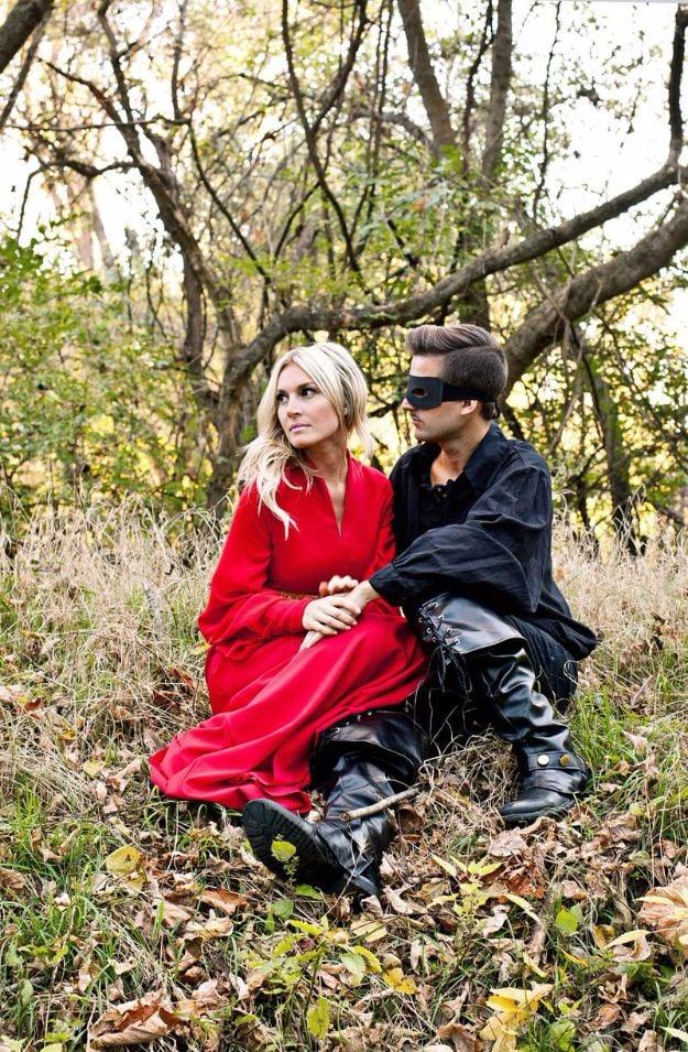 Princess Bride couples costume with a red Buttercup gown and gold trim beside Westley in black with a mask