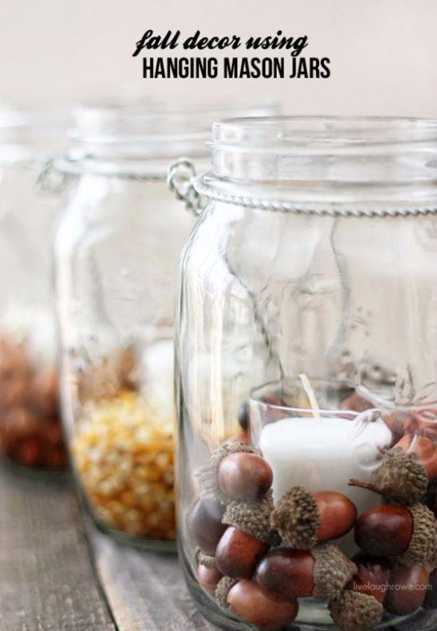 Pin graphic titled fall decor using hanging mason jars showing jars filled with popcorn kernels and acorns