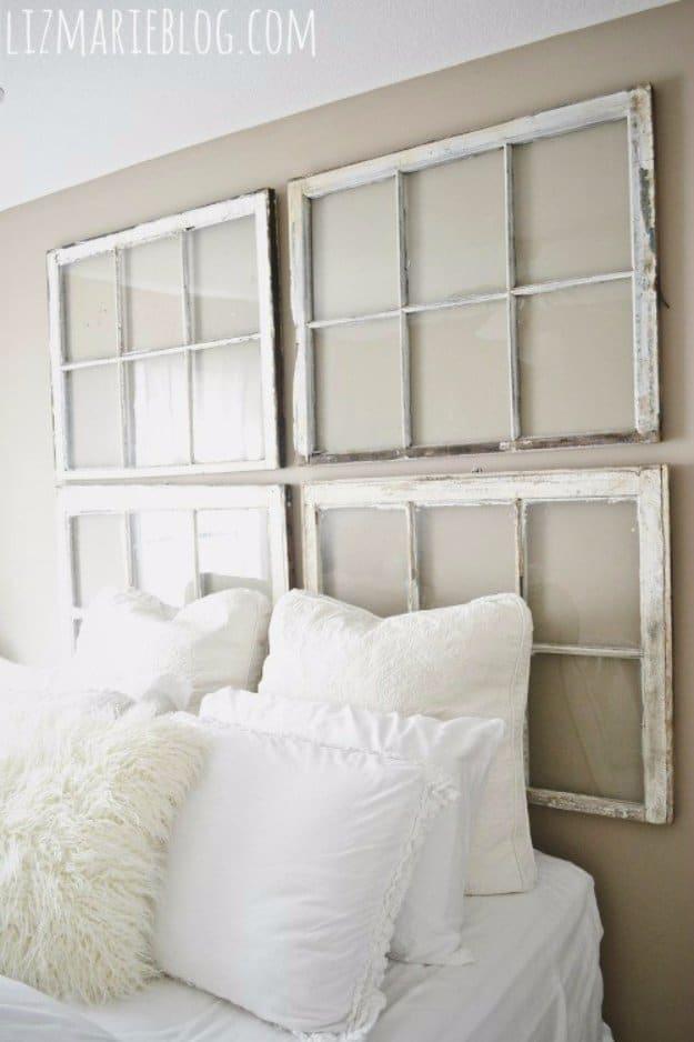 DIY antique window headboard, four chippy white salvaged window sashes hung above a bed piled with white bedding