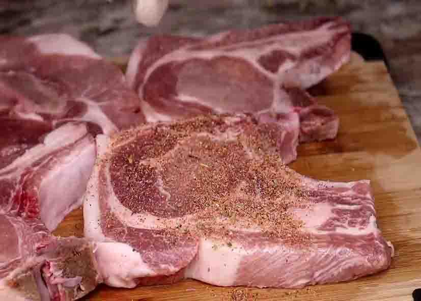 Rubbing the seasonings onto the pork chops
