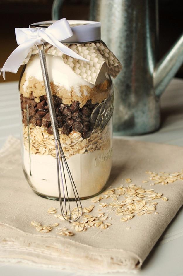 Mason jar of layered oatmeal chocolate chip cookie mix with a small whisk tied on top with a ribbon bow